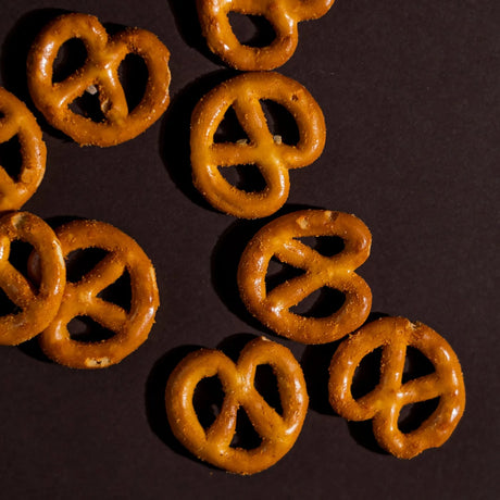 Closeup of baked BBQ pretzels arranged neatly on brown background Elsouk
