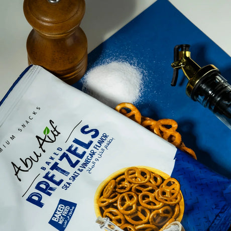 Flat lay of pepper flavored pretzels with spice grinder by Elsouk