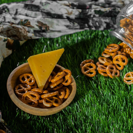 Cheese flavored pretzels in bowl with cheese slice on grass Elsouk