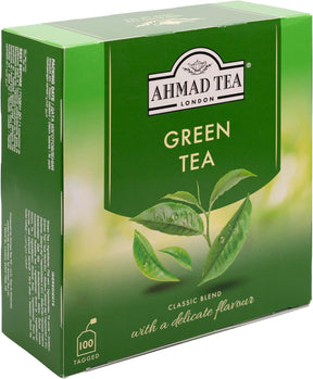 A box of Ahmad Tea Green Tea with green tea leaves and packaging, showcasing the brand and fresh, natural tea leaves inside.