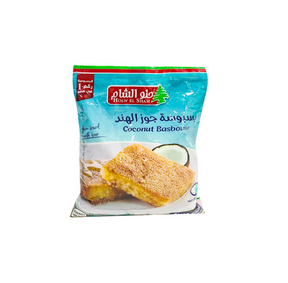 Slice of Holw El Sham Basbousa with coconut, a traditional Middle Eastern treat with shredded coconut topping, on a white plate.