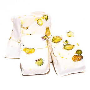 Piece of Master Delight pistachio nougat with visible pistachio nuts on a white background.