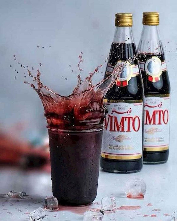 A glass filled with Vimto فيمتو soft drink, showcasing its deep purple color and refreshing appearance.
