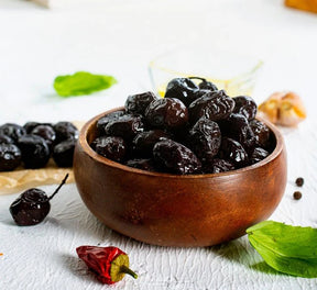 Judi Atton black olives in a 600g jar, shiny and ripe, ready for snacking or cooking, displayed in a clear container.